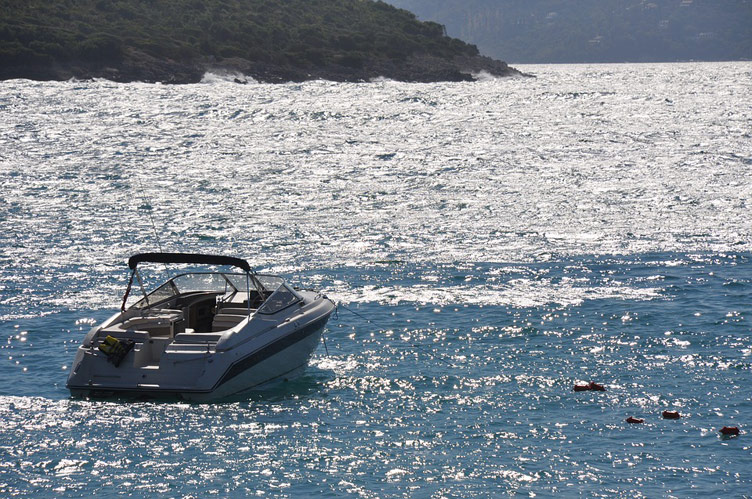 Photo of speedboat in the blue sea on a beautiful sunny summer's day in Albania's region of Saranda with mountains visable ahead in the distance