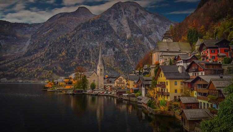 Beautifully coloured buildings of Hallstatt village sitting on lakeside surrounded by mountains