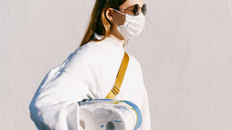 A woman carrying toilet paper pack wearing a coronavirus mask