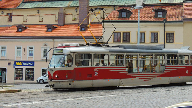 A red and white trolleybus set against old town buildings in a street in Prague 