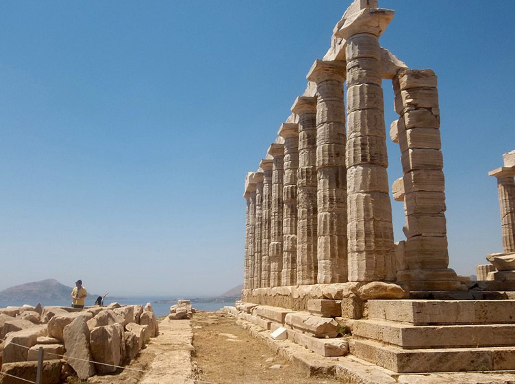 Ancient ruins of the Temple of Poseidon set against a clear blue sky