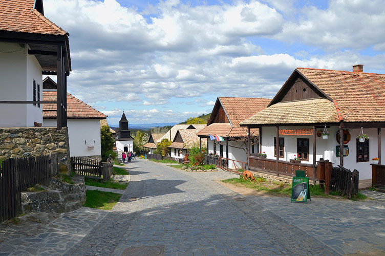 A street with white-washed clay houses on both sides of the street in the old village of Holloko