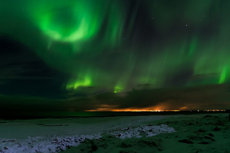 A beautiful skyline lit by the green light of aurora, aka the Northern Lights, at nighttime