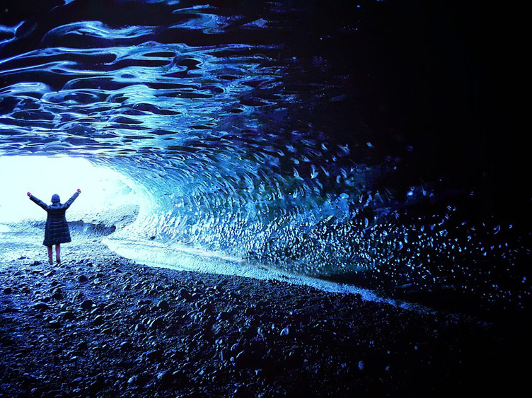 Photographed from inside icecave is a person standing at the entrance of the cave in Skaftafell, Iceland