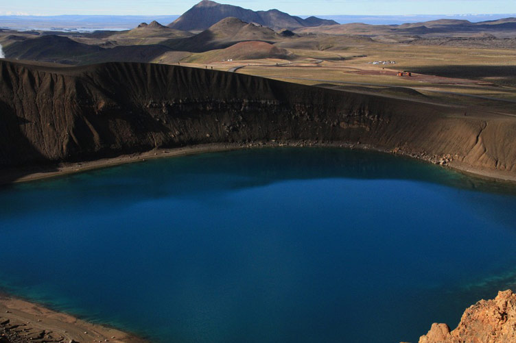 Perfectly blue waters of Viti crater lake against brown volcanic slopes in Krafla