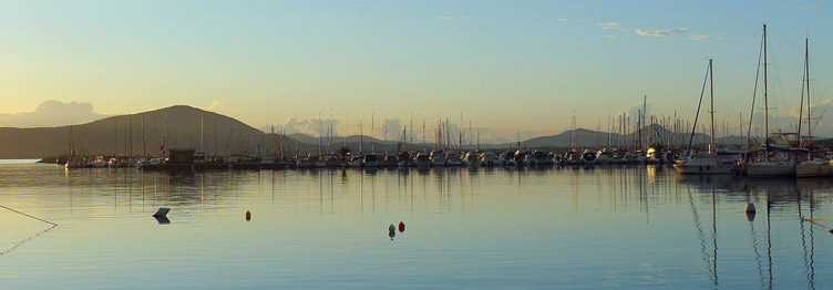 Sunset view of the boats and yachts docked in Alghero Marina di S.Elmo harbour, in Sardinia.  width=98%