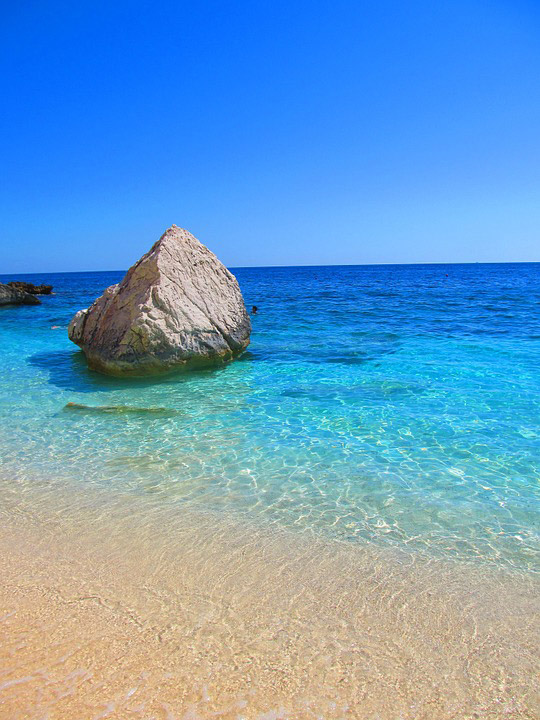 Beach rock perched in sea water on Cala Mariolu beach in Sardinia width=98%