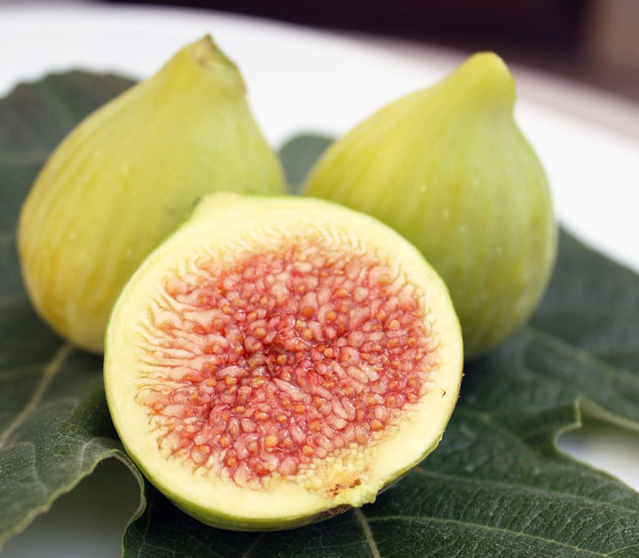 Close up of fresh Mediterranean figs. The fig at the front of the photographic composition is sliced in half and we can see the inside of the fig. 