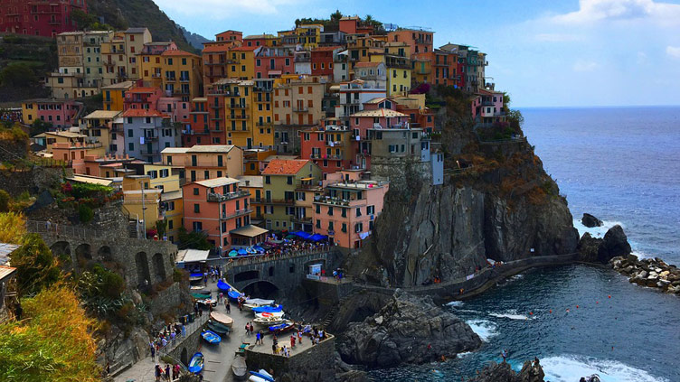 Colourful Manarola village on a cliffside surrounded by water on one side