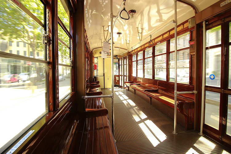 A slick wood interior of an empty vintage tram in Milan featuring stunning wood benches