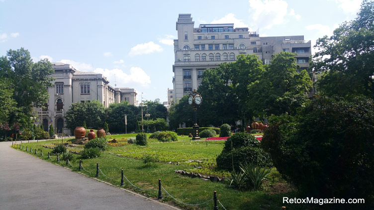 An entrance to Cismigiu Gardens with very large traditional Romanian clay-style vases and pottery decorating the green areas of the entrance 