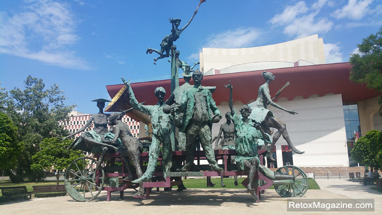 Um grande Caragealiana escultura de um carro com vários personagens posicionados na frente do Teatro Nacional de Bucareste