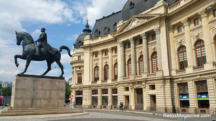 La photographie présente une vue latérale d'une statue d'un cavalier à cheval ainsi que la magnifique façade avant de la Bibliothèque centrale du bâtiment universitaire de Bucarest