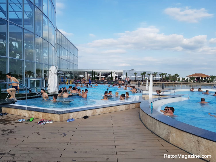 mensen die overdag genieten van de fantastische buitenzwembaden van Therme Bucuresti