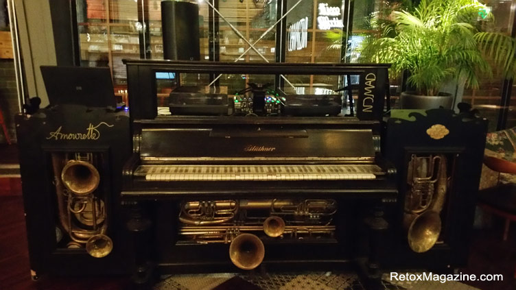 een oude piano en andere instrumenten upcycled om een unieke artisanale DJ station gepositioneerd in een bar