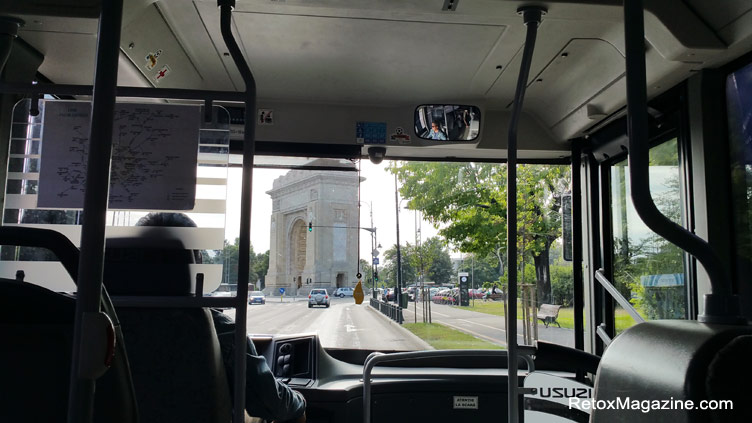 het uitzicht vanuit de bus die door het raam kijkt en een beroemd boogmonument in Boekarest ziet