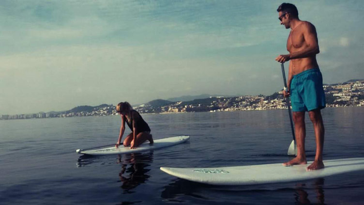 Two people partaking in a pad-dle surf class on the water at El Palo beach on Malaga coast in Spain