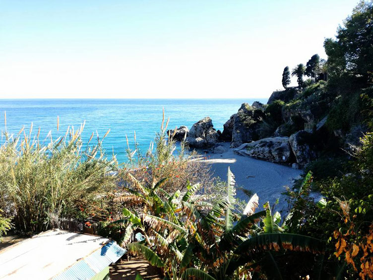 A beautiful beach in Nerja surrounded by rocks and plants, Spain