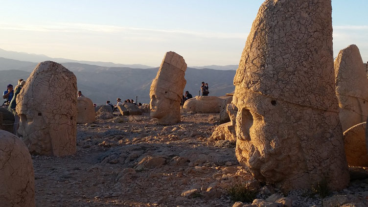 Gigantic statue heads on Mount Nemrut set against the backdrop of mountains and hills in the distance