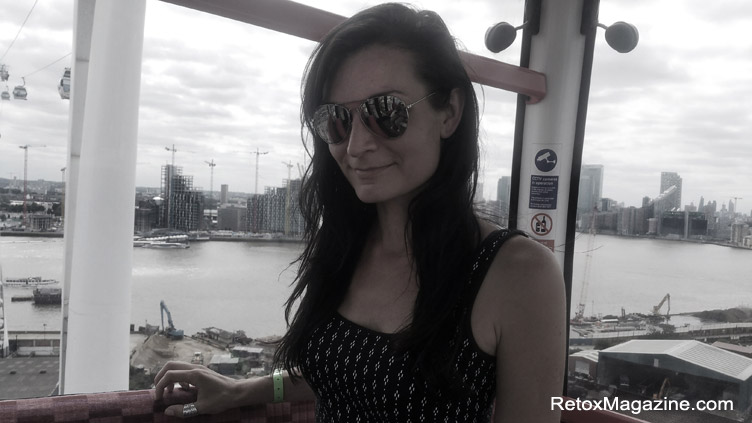 A black and white photo of a woman inside the Emirates Air Line Cable Car riding over the River Thames.