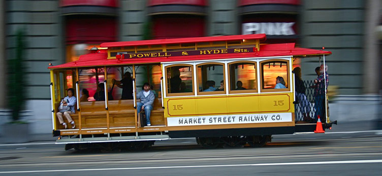 A quirky looking iconic red and yellow vintage tram of san francisco photogrpahed in motion