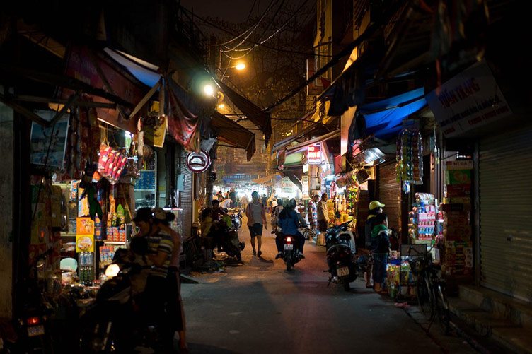 People shopping in a typical asian street market in Hanoi city at night under streetlights